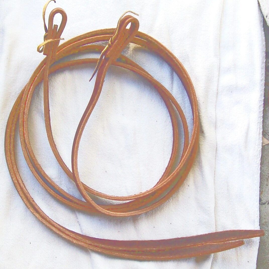Leather reins coiled on white fabric